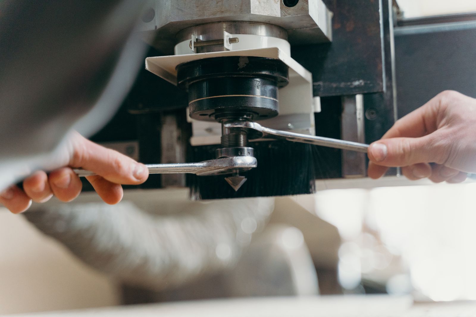An operator changing tooling on an industrial machine with two wrenches mid-changeover